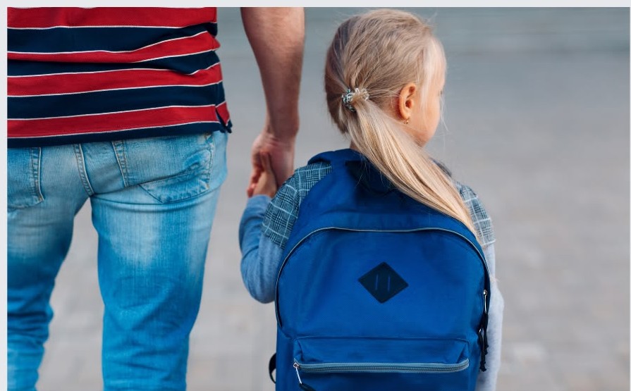 Pai e filha de mochila a caminho da escola, de mãos dadas