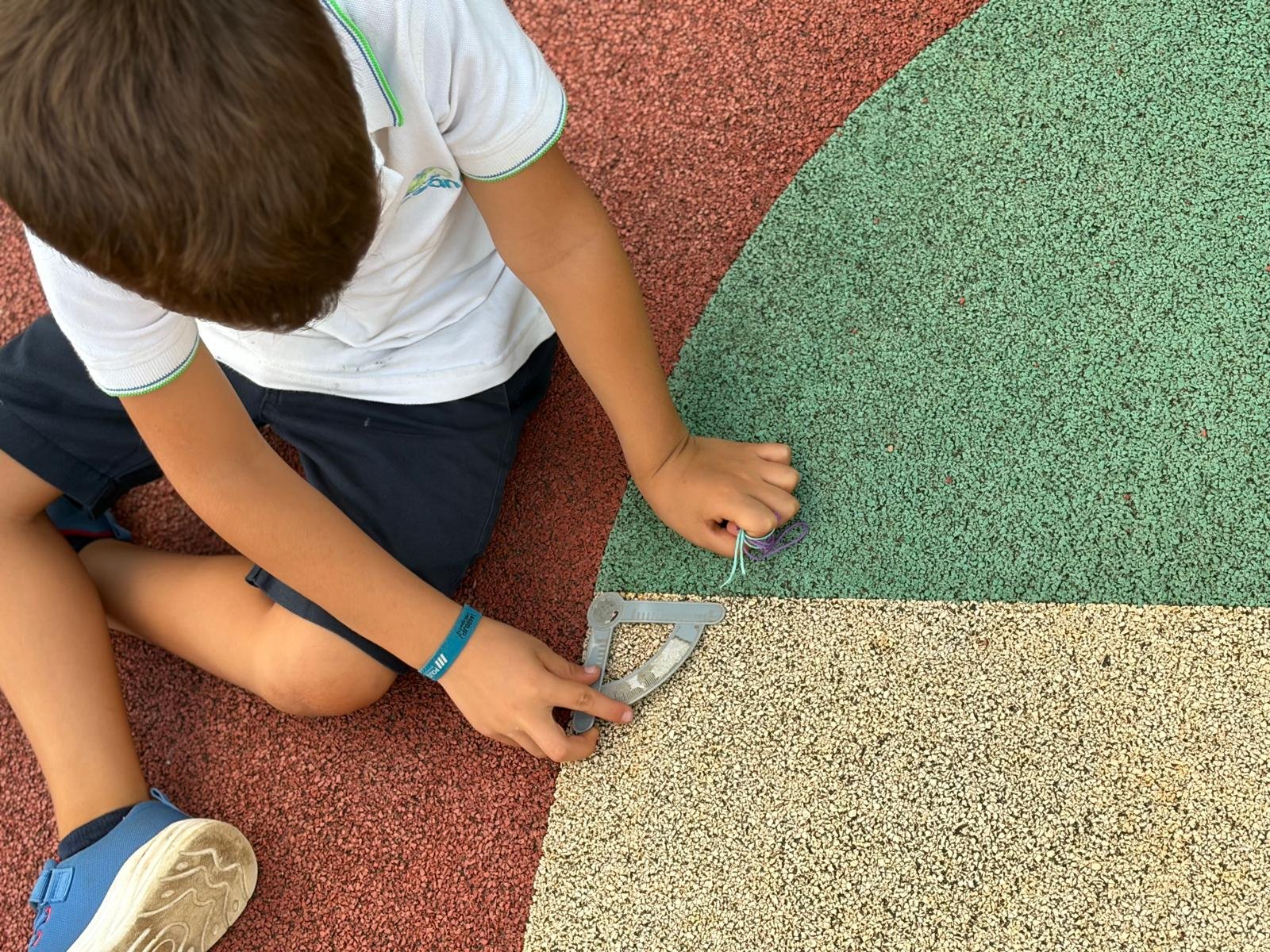 Esquadro colocado sobre o encontro de diferentes superfícies coloridas do recreio